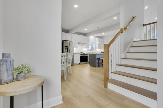 interior space with beamed ceiling, stairway, light wood-type flooring, and recessed lighting