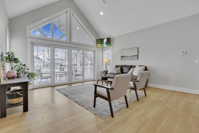 living room featuring high vaulted ceiling, recessed lighting, light wood-style flooring, and baseboards