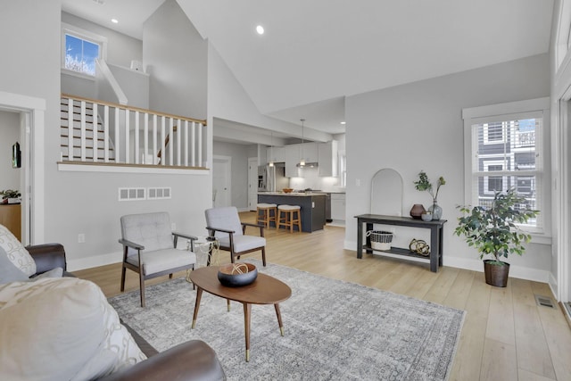 living room with baseboards, stairs, and light wood-style floors