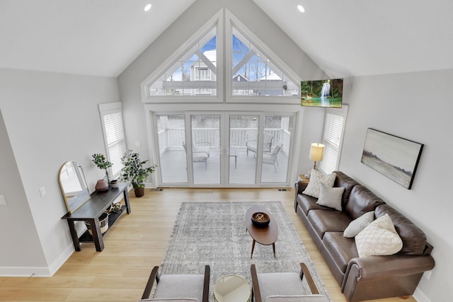 living room with a healthy amount of sunlight, high vaulted ceiling, baseboards, and wood finished floors