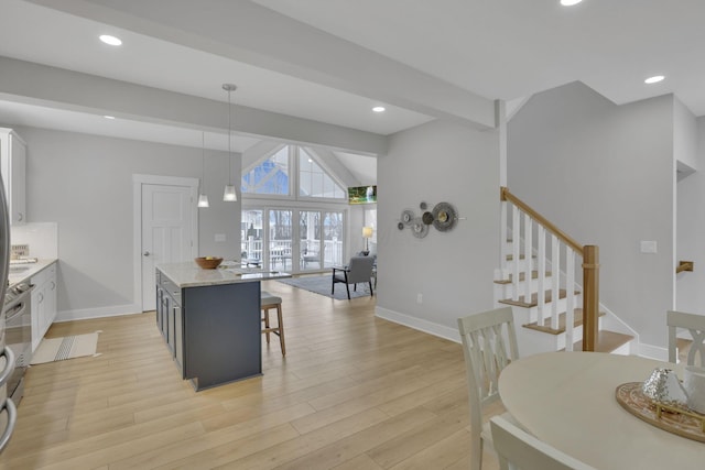 kitchen featuring baseboards, decorative light fixtures, light wood-type flooring, a kitchen bar, and recessed lighting