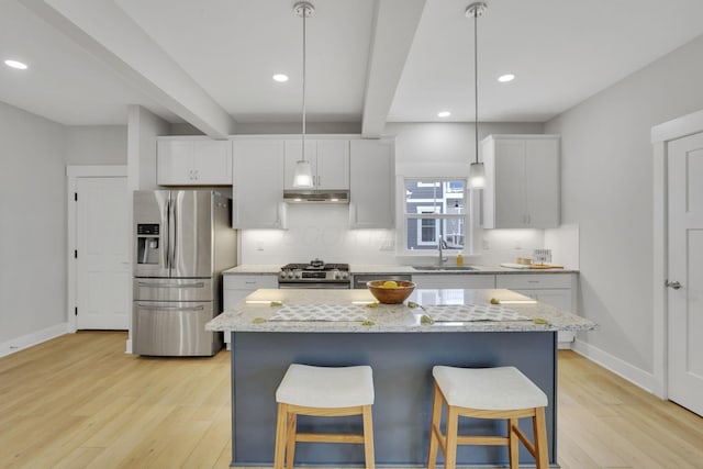 kitchen with stainless steel appliances, tasteful backsplash, light wood-type flooring, and a sink