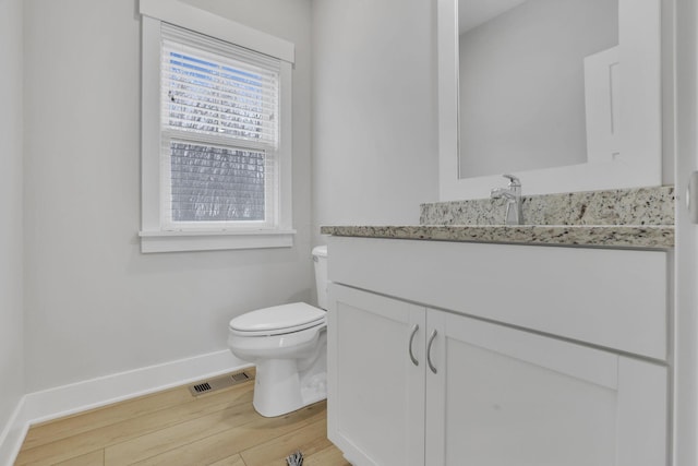 bathroom featuring visible vents, toilet, vanity, wood finished floors, and baseboards