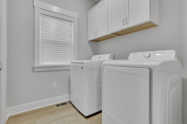 laundry room with cabinet space, visible vents, baseboards, light wood-type flooring, and washing machine and dryer