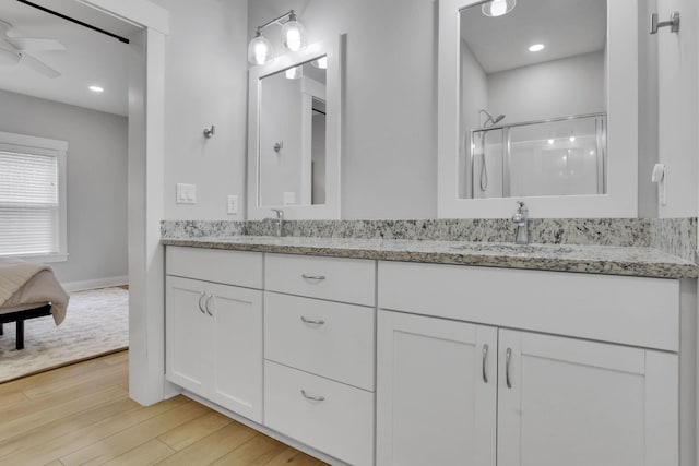 bathroom featuring ceiling fan, a sink, a shower stall, and wood finished floors