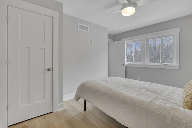 bedroom featuring baseboards, visible vents, ceiling fan, and light wood finished floors