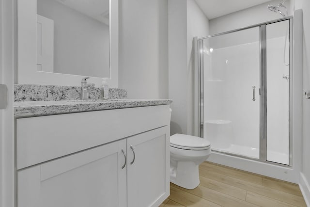 bathroom featuring toilet, a shower stall, wood finished floors, and vanity