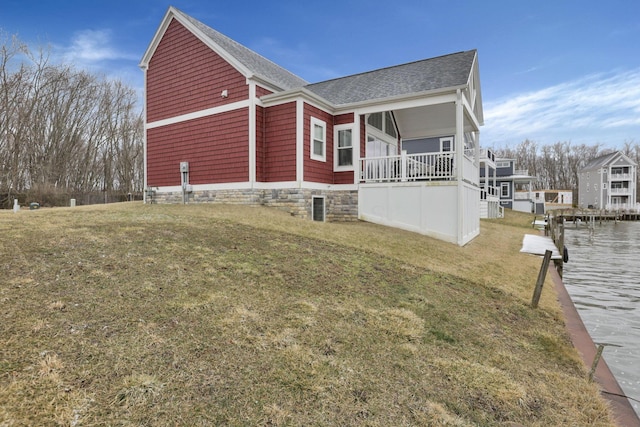 view of home's exterior with a shingled roof, a lawn, and a boat dock