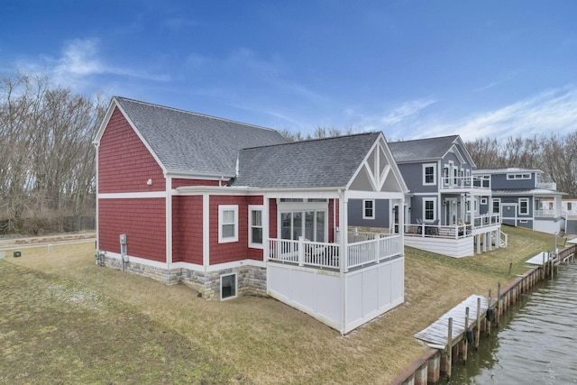 rear view of property with a yard, a shingled roof, and a balcony