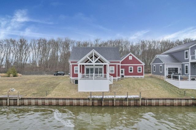 rear view of property featuring a yard, a shingled roof, and a water view