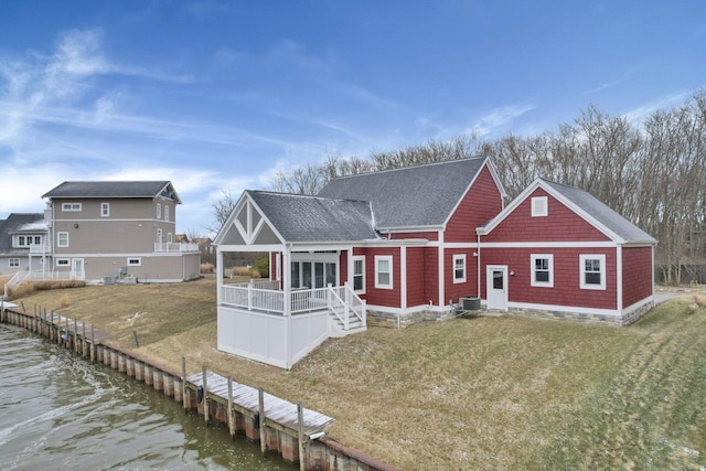 back of house featuring central AC unit, roof with shingles, a deck with water view, and a lawn