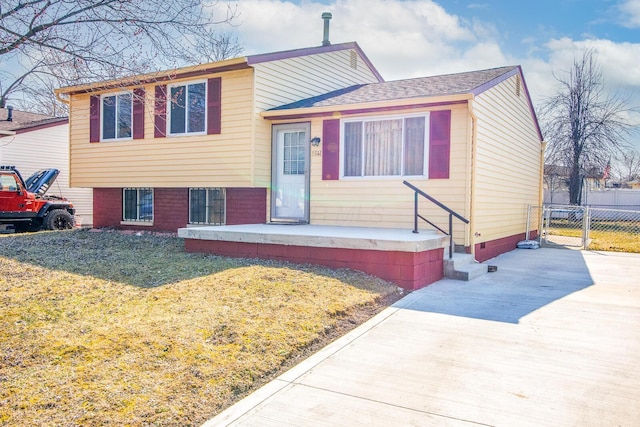 tri-level home featuring a gate, concrete driveway, a front yard, and fence