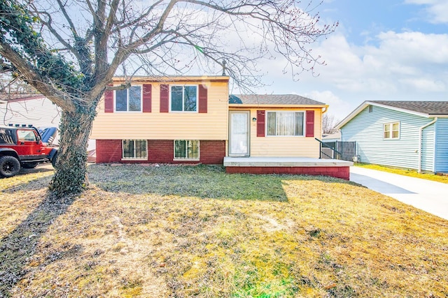 split level home featuring brick siding and a front yard