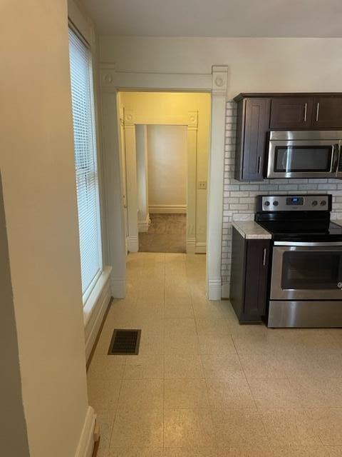 kitchen featuring dark brown cabinetry, stainless steel appliances, visible vents, baseboards, and light countertops