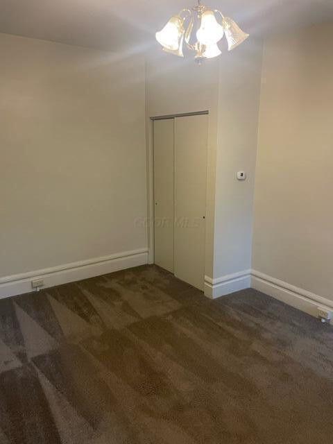 unfurnished bedroom featuring dark colored carpet, a closet, and baseboards