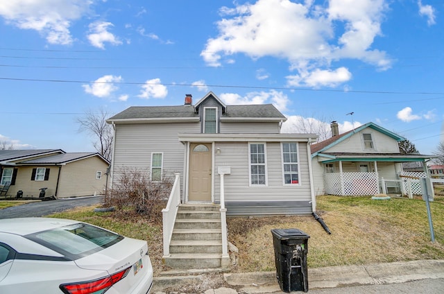 bungalow with a shingled roof, a chimney, and a front lawn