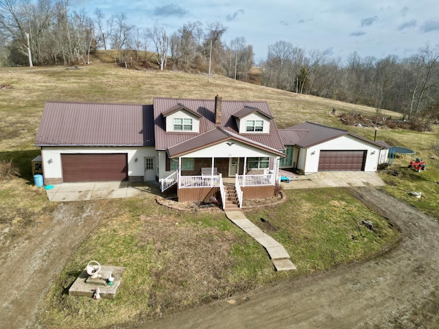 view of front of property with driveway, a garage, metal roof, covered porch, and a front yard