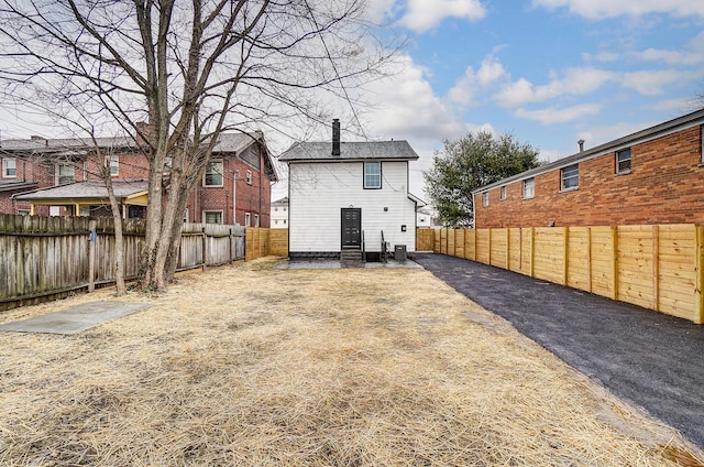 back of property with entry steps and a fenced backyard