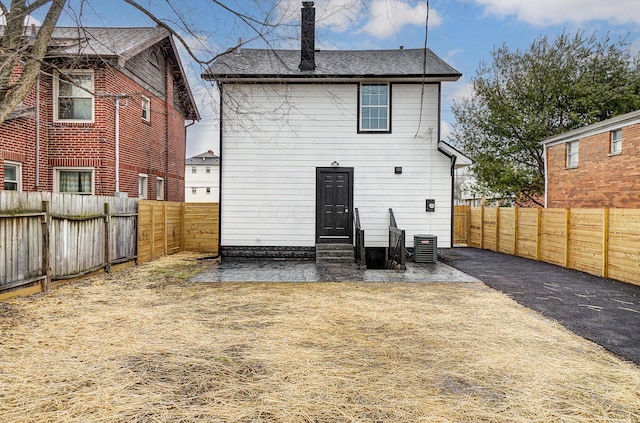 rear view of property featuring entry steps, a patio area, a fenced backyard, and central air condition unit