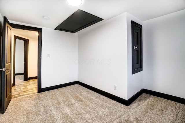 spare room featuring light carpet and baseboards