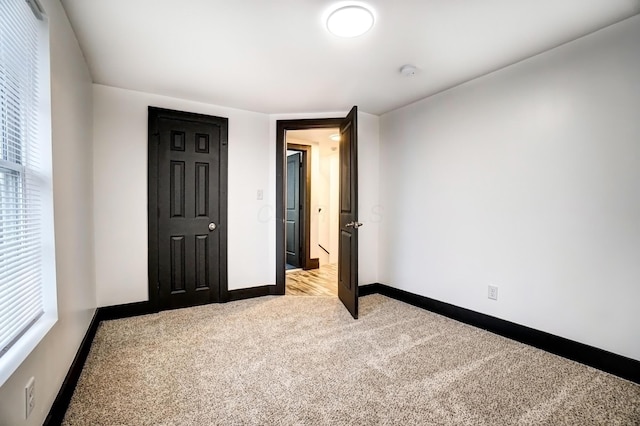 unfurnished bedroom with baseboards and light colored carpet