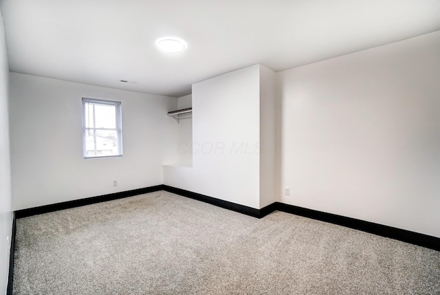 empty room with carpet floors, visible vents, and baseboards