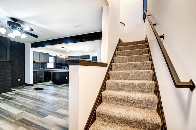 stairway with baseboards, a ceiling fan, and wood finished floors