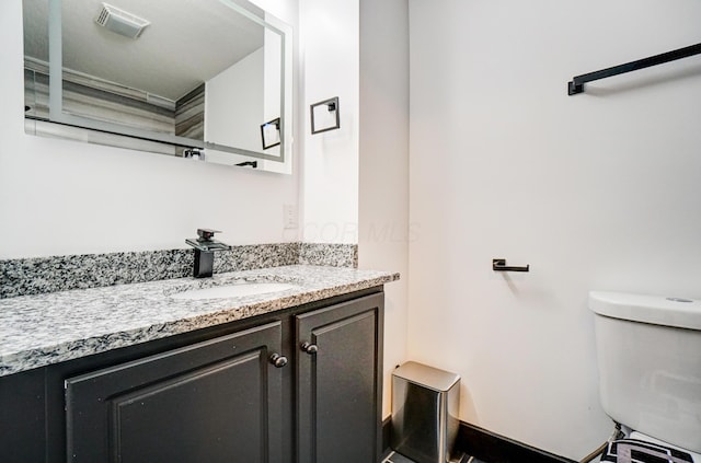 bathroom with toilet, visible vents, and vanity