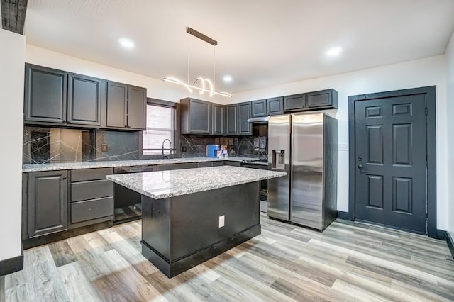 kitchen featuring light stone counters, black dishwasher, light wood finished floors, a kitchen island, and stainless steel fridge with ice dispenser