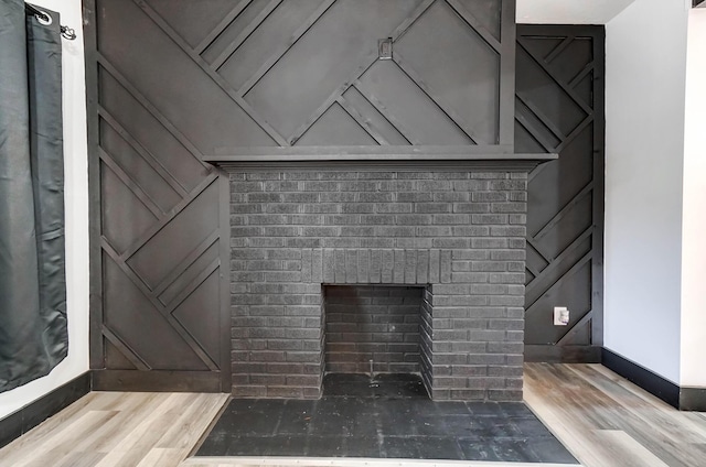 room details featuring a brick fireplace, wood finished floors, and baseboards