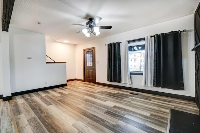 interior space with a ceiling fan, a wealth of natural light, light wood-style flooring, and baseboards