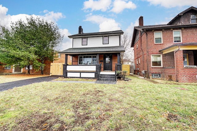 american foursquare style home with a chimney, fence, a porch, and a front yard