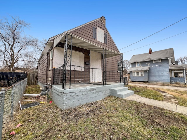 view of front facade featuring a chimney, fence, and a porch