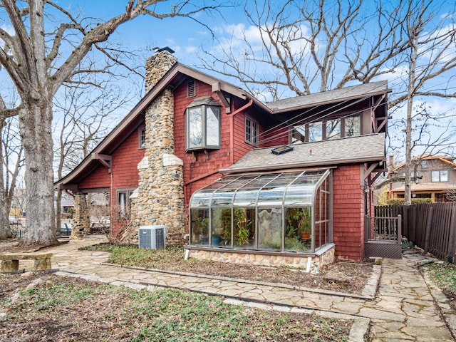 back of house featuring a sunroom, a chimney, roof with shingles, fence, and cooling unit