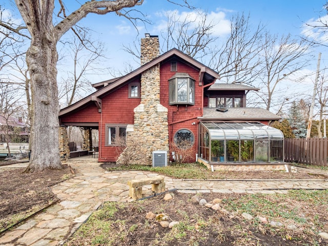 back of house with central AC unit, a sunroom, a chimney, fence, and a patio area