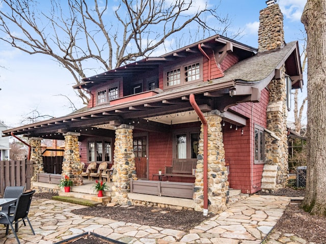 rear view of house with a shingled roof, a chimney, a patio area, and fence