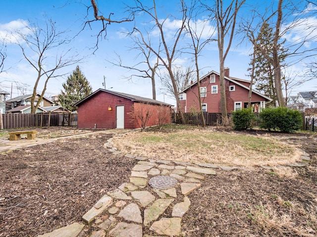 view of side of property featuring fence, a chimney, and an outdoor structure