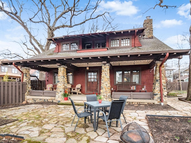 rear view of property with roof with shingles, a chimney, a patio area, and fence