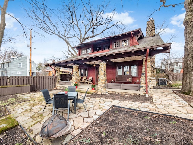 rear view of house featuring a patio area, a chimney, fence, and outdoor dining space