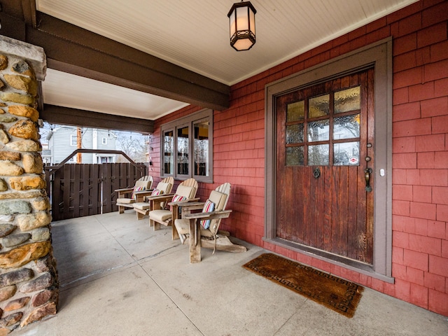 property entrance with covered porch and fence