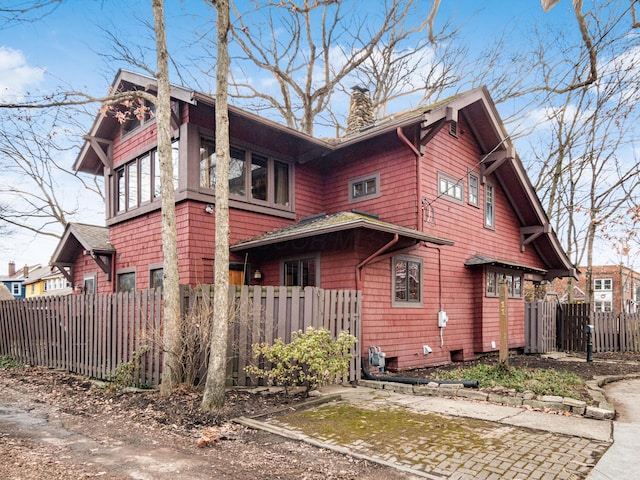 view of property exterior featuring a chimney and fence