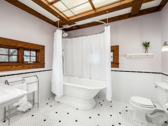 full bathroom with a tub to relax in, curtained shower, tile patterned flooring, tile walls, and wainscoting