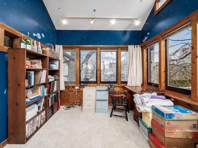 carpeted office with track lighting, vaulted ceiling, and built in desk