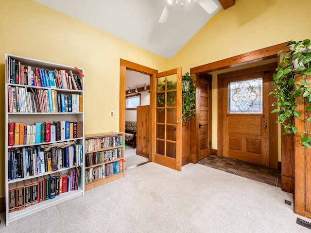 carpeted foyer with vaulted ceiling, visible vents, and a ceiling fan