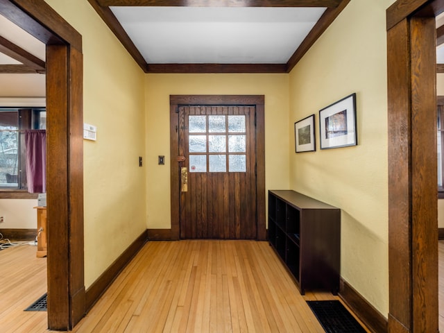 doorway to outside featuring light wood-style floors, baseboards, and crown molding