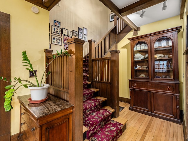 stairs with hardwood / wood-style floors, beam ceiling, and baseboards