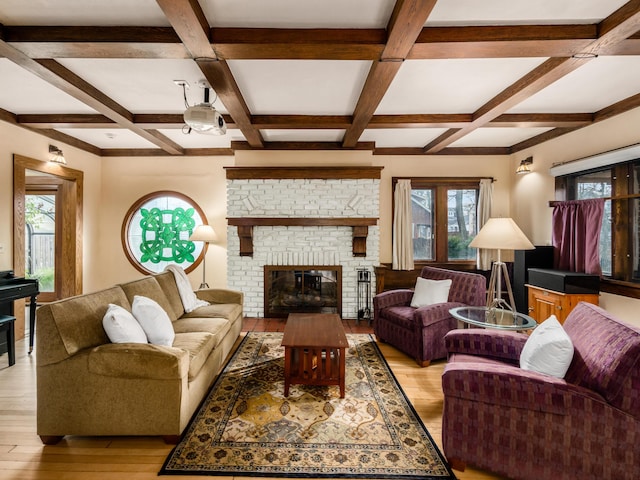 living room with coffered ceiling, a fireplace, beamed ceiling, and light wood finished floors