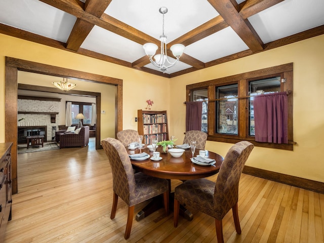 dining area with baseboards, light wood finished floors, coffered ceiling, and an inviting chandelier