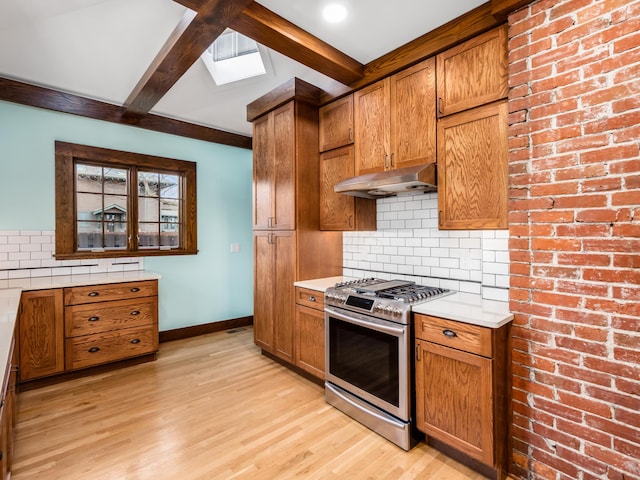 kitchen with brown cabinetry, stainless steel gas stove, beamed ceiling, and under cabinet range hood