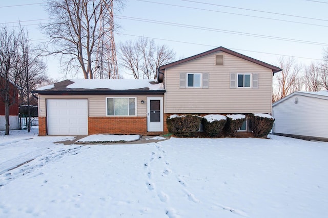 split level home featuring a garage and brick siding